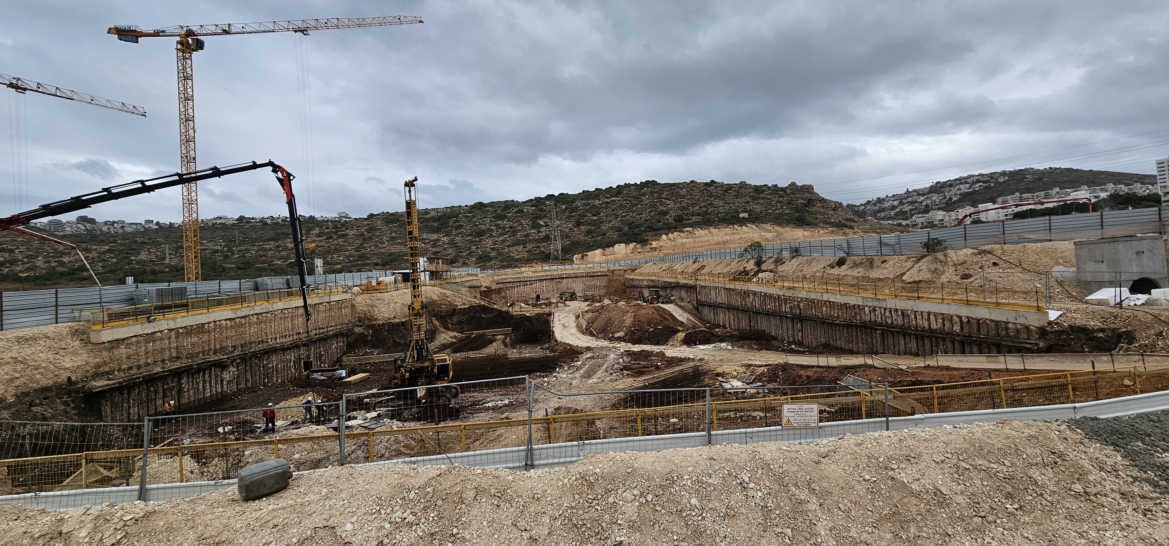 אתר בנייה נרחב על גבעות עם מספר עגורני מגדל, בשעת שקיעה